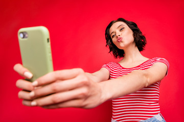 Naklejka premium Low angle view portrait of her she nice attractive lovely lovable cheerful cheery wavy-haired girl taking making selfie sending you kiss isolated over bright vivid shine red background