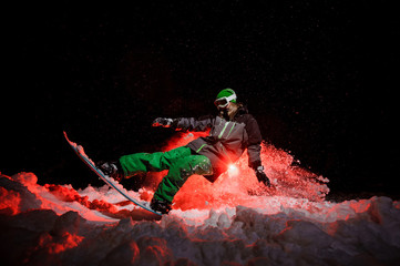 Active female snowboarder dressed in a green sportswear performs tricks on the mountain slope
