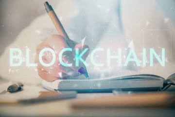 Cryptocurrency hologram over woman's hands writing background. Concept of blockchain. Double...