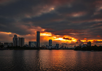 Cloudy sunset over Yekaterinburg business center reflecting in water of pond