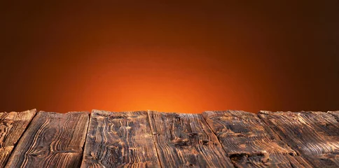 Schilderijen op glas Old rustic wooden table top with warm orange glow © exclusive-design