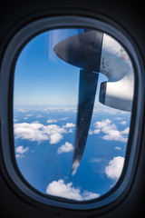 Window with a view: Window of a turboprop plane with engine, propeller blue sky, clouds and ocean, Azores Islands, Portugal