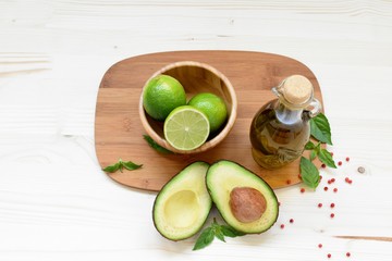 Top dish of vegetarian food with avocado, limes and olive oil on white background.