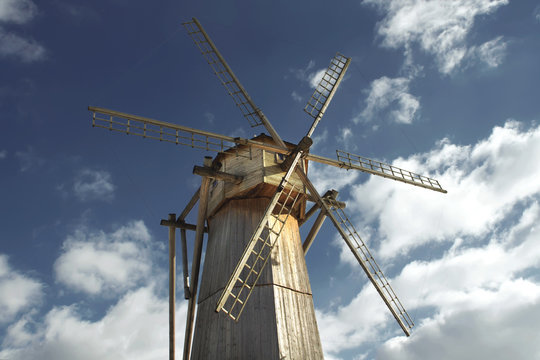 Old wooden windmill against a blue sky in sunny day close-up