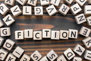fiction - word from wooden blocks with letters, Literary Genres concept, random letters around, top view on wooden background