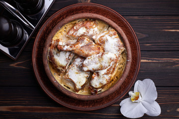 Chkmeruli chicken on a dark background on a wooden board