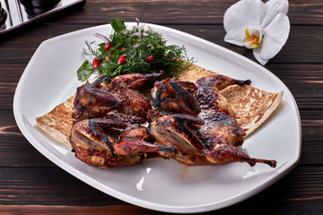 Fried quail on a plate on a wooden board