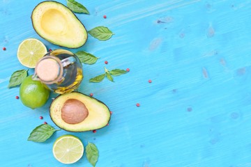 Top table concept with avocado, olive oil, limes and mint leaves on blue background. Copy text space