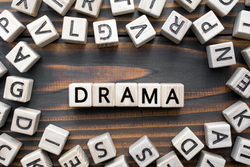 drama - word from wooden blocks with letters, Literary Genres concept, random letters around, top view on wooden background