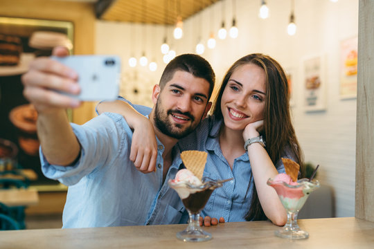 happy couple taking picture while eating ice cream indoor