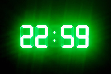 Green glowing digital clocks in the dark show 22:59 time