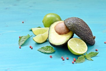Top dish with natural avocado, limes and mint leaves on blue background.