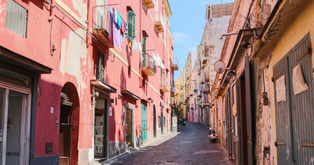 Fototapeta na wymiar Daylight view on a colorful street of Procida island a sunny summer day. This italian island is famous for its vibrant pastel old houses and the Marina Corricella. Italy (Campania) – Image