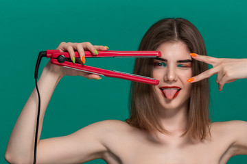 Portrait of beautiful young woman with bright color make-up doing hair style herself with a purple...