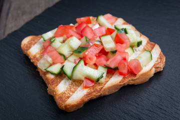 Vegetarian bread toast bruschettas with fresh cucumber and tomato.