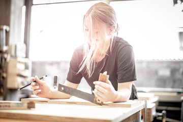 junge Handwerkerin mit Winkel und Stift in der Schreinerei