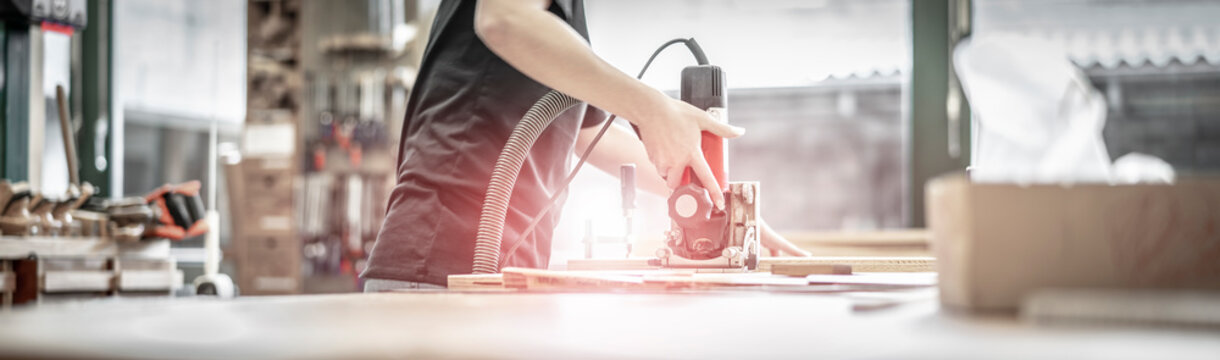 junge Frau bearbeitet mit der Lamellofr&auml;se Schichtholzplatten aus Seekiefer in der Holzwerkstatt