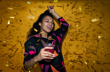 Young happy african girl black woman holding drink glass dancing at night club party with glitter...