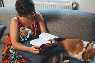 woman relaxed in sofa reading book at her home