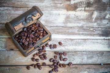 Coffee beans in the old chest on old wooden table background.