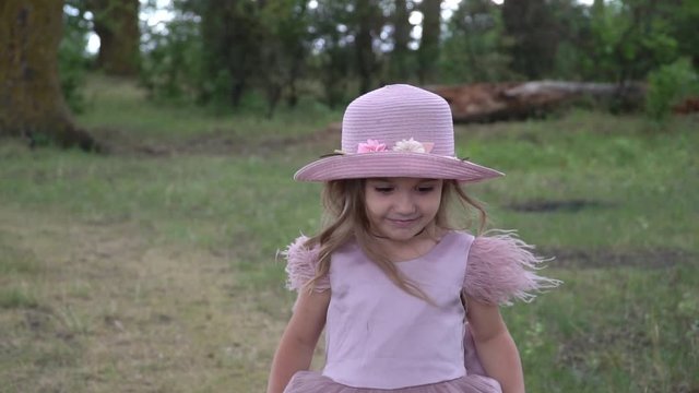 little beautiful girl in a beautiful pink dress walking in nature, slow motion, close-up