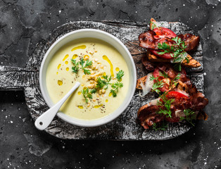 Sweet corn mashed soup with bacon tomato parmesan whole grain bread toast on dark background, top view
