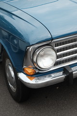 Scheinwerfer und Kühlergrill einer blauen Limousine der Sechzigerjahre aus der Sowjetunion und...
