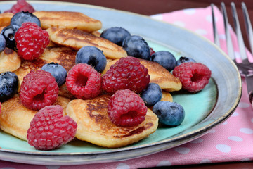 Delicious pancakes with berries and maple syrup on table