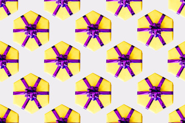 Festive pattern of yellow gift boxes on a gray background.
