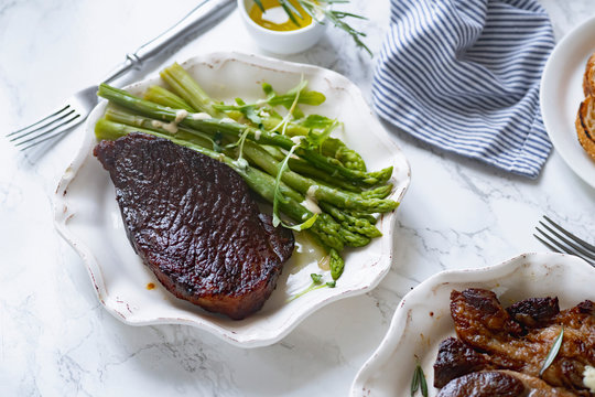Cooked black angus prime beef steak with asparagus and cream mustard sauce. Top view dinner picture.