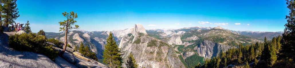Yosemite National Park, California / USA - September 2nd, 2012: Panoramic view from the Glacier Point with the Half Dome in the center / Some visitors watching the views from a viewpoint telescope