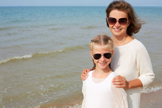 Summer vacation, adoption and people concept. Happy woman and little girl  having fun over blue sky background