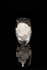 verre d'eau et glaçons  sur fond noir brillant