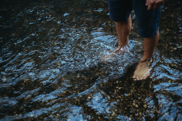 flowing water around the ankles of a human feet standing in a river