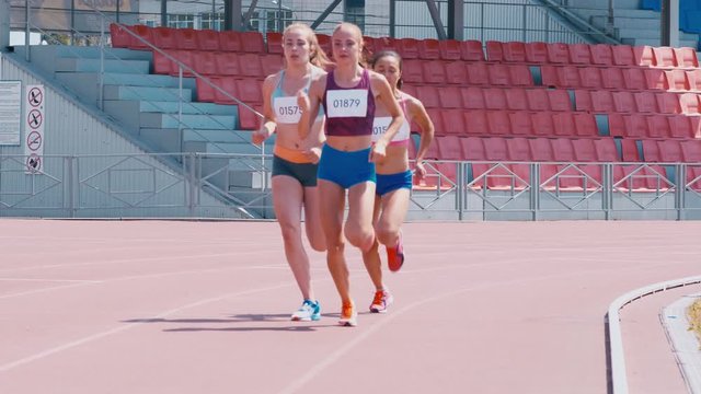 Tilt down shot of young girls running track race on arena