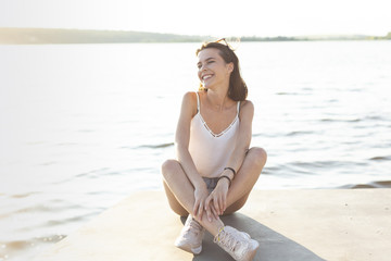 Fototapeta na wymiar Long shot woman posing while sitting on a dock