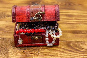 Vintage treasure chest full of jewelry and accessories on wooden background