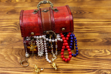 Vintage treasure chest full of jewelry and accessories on wooden background