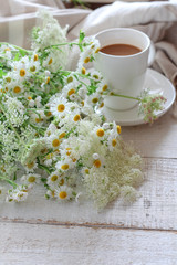 Summer morning table with a cup of coffee and wild flowers 