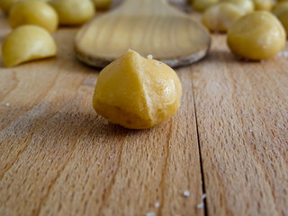 Macadamia on wooden spoon, wooden and blurry background close up 