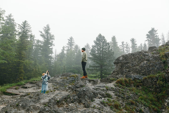 Young woman taking picture of her husband. Travelling together in the mountains
