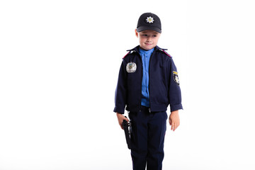 Cute sad little police boy with smile on face and gun on white background. Intelligent cool children in police suit with blue eyes and weapon