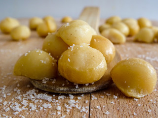  Macadamia on wooden spoon, wooden interface and blurry background salty close up 