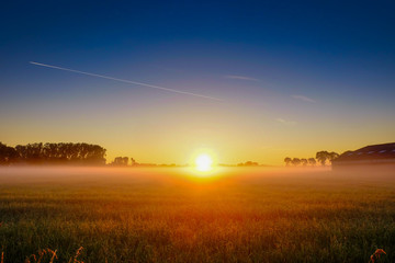 Colorful glowing sunrise over a countryside farming area, creating an idyllic scenic landscape