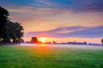 Fototapeta na wymiar Colorful glowing sunrise over a countryside farming area, creating an idyllic scenic landscape