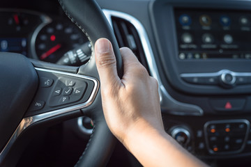 Asian man hand holding steering wheel with audio control and call buttons