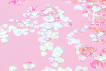 Fototapeta na wymiar Heart holographic confetti sparkles on pink background