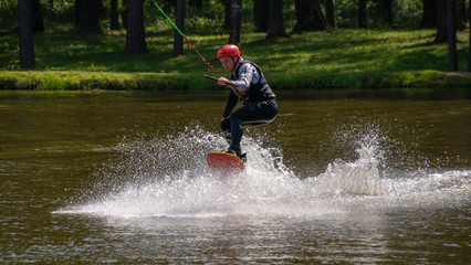 Wakeboarder training on the wide water surface of the pond in the recreation Park