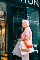 Happy pensioner entering clothes shop and smiling