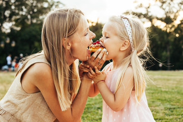 mom and daughter eating healthy and enjoying a family picnic on warm sunny summer day